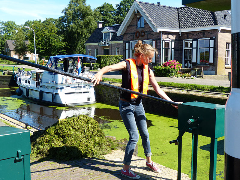 De groene sluizen van Lippenhuizen en Wijnjeterp. Sluiswachters hengelen de waterplanten uit de kolk. Fotografie: Jana Hendriks, Friesland Holland Nieuwsdienst